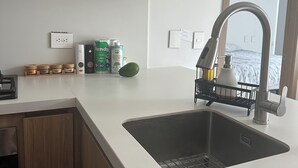 A modern kitchen with a stainless steel sink, wooden cabinets, and a window providing a view.