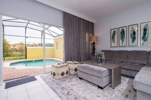 Un salón moderno con un sofá gris, una mesa de centro y vista a la piscina.