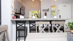 A kitchen with a central island, bar stools, and pendant lighting.