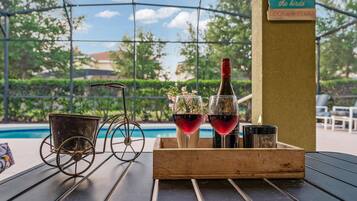 A table with a candle, two glasses of red wine, and a metal bicycle wheel.