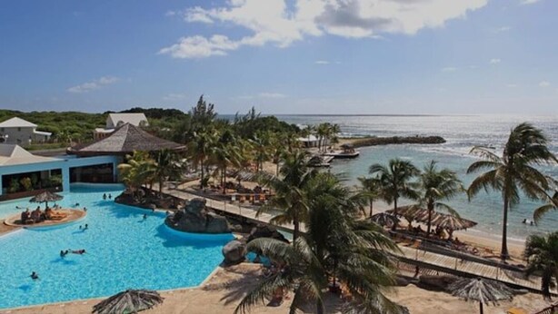 Ein Resort mit großem Pool, Palmen und Blick auf den Ozean.