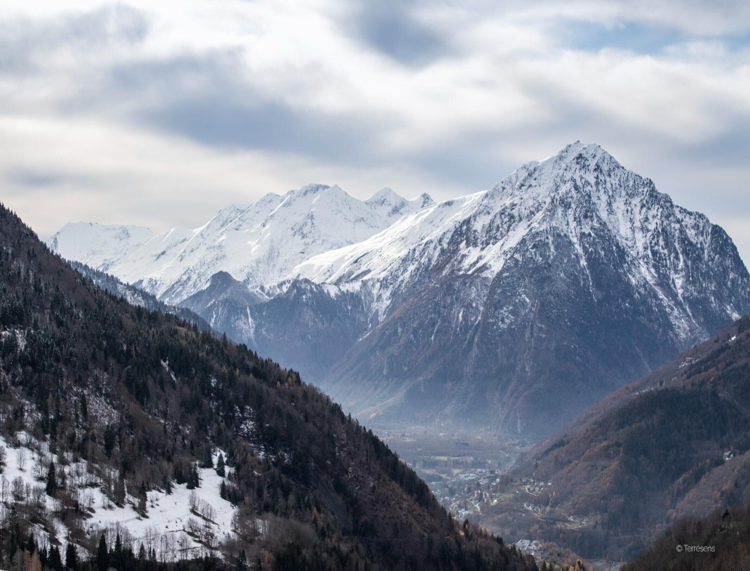 Un paysage montagneux avec des sommets enneigés et une vallée.