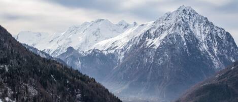 Un paysage montagneux avec des sommets enneigés et une vallée.