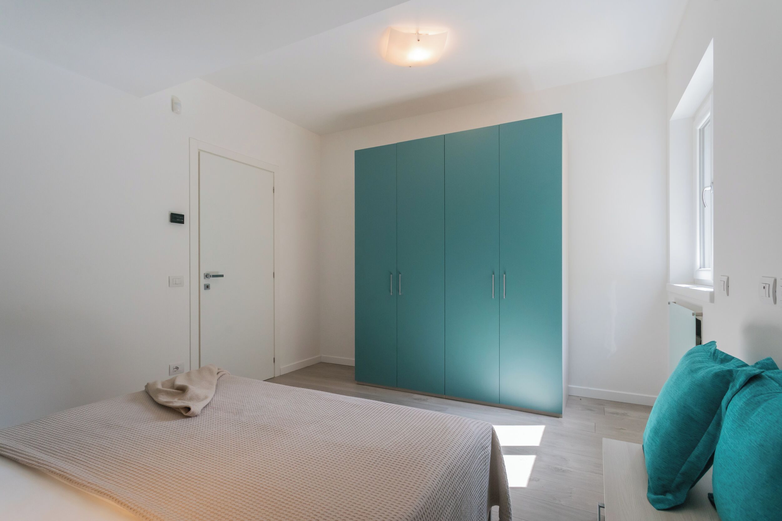Un dormitorio con cama, armario y ventana.
