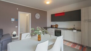 Une cuisine moderne avec des meubles blancs, une touche de rouge et une horloge au mur.