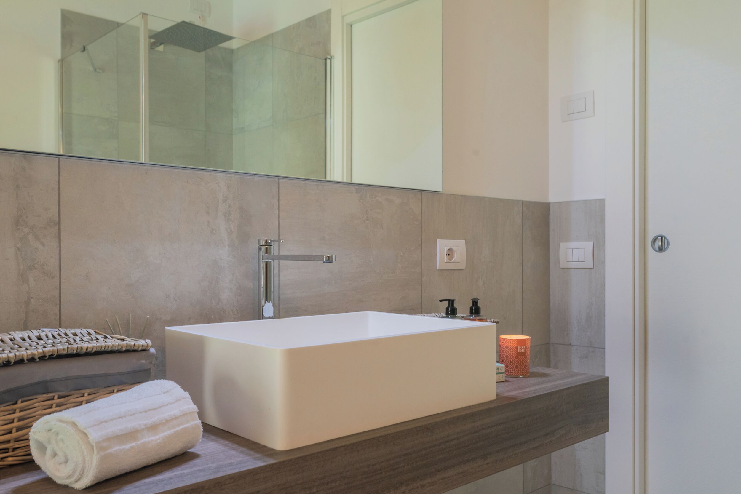 A modern bathroom with a large rectangular sink, a mirror, and a shower area.