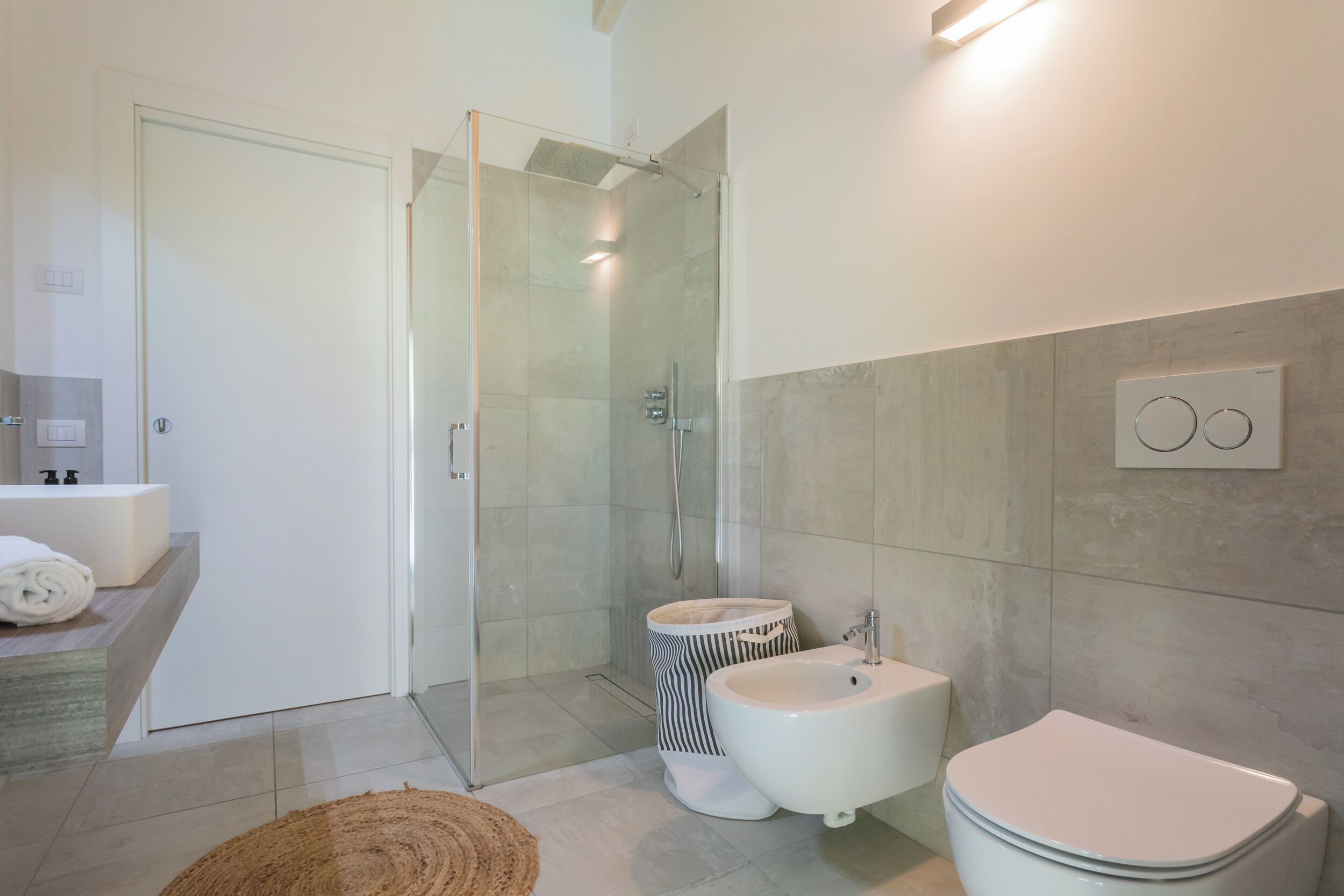 A modern bathroom with a glass-enclosed shower, a white sink, and a toilet.