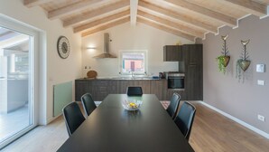 A modern kitchen with a dining area, featuring a large wooden ceiling, dark cabinets, and a central island with a bowl.