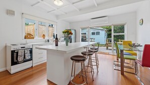 Una cocina moderna con una isla central, taburetes de bar y un comedor con mesa y sillas.