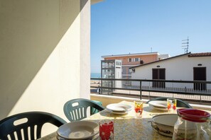 Ein Balkon mit Esstisch, Blick auf ein Gebäude und einen klaren Himmel.