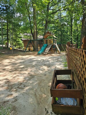 A playground with a slide and climbing structures, surrounded by trees. - Mountain Cabin for PGA TOUR Week in Asheville (Asheville)