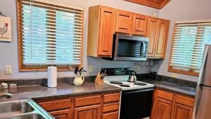 A kitchen with wooden cabinets, a stainless steel sink, a stove, and a microwave.