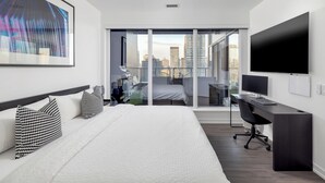 A modern hotel room with a large bed, a desk with a computer, and a TV.