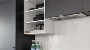 A modern kitchen with dark cabinetry, white countertops, and stainless steel appliances.