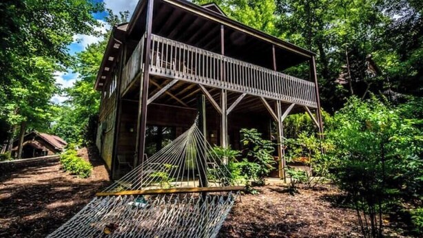 A wooden cabin with a balcony, surrounded by trees.