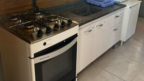 Une cuisine équipée d’une cuisinière, d’un four, d’un évier et d’une fenêtre avec des rideaux.