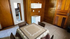 Une pièce aux murs lambrés, avec une table à manger dressée pour quatre personnes, entourée de chaises en osier.
