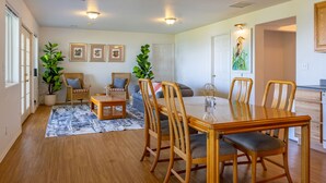 Ein Essbereich mit Holztisch und Stühlen, einer Couch und einem Blumentopf.