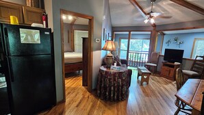 A spacious kitchen with wooden beams, a dining area with a round table, and a cozy living room with a TV and seating.