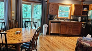 A spacious kitchen with wooden cabinets, a stainless steel dishwasher, and a dining area with a wooden table and chairs.