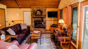 A cozy living room with a stone fireplace, leather sofa, and a dining area with a table and chairs. - Trade the Hotel for a Hot Tub During PGA TOUR Asheville (Asheville)