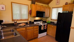 A kitchen with wooden cabinets, a stove, a refrigerator, and a sink. - Trade the Hotel for a Hot Tub During PGA TOUR Asheville (Asheville)