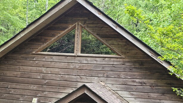 A rustic wooden cabin with a steeply pitched roof, a front porch, and a visible door. - Your PGA TOUR Basecamp in the Blue Ridge Mountains (Asheville)