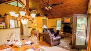 A cozy cabin interior with a dining area, living room, and fireplace. - Your PGA TOUR Basecamp in the Blue Ridge Mountains (Asheville)