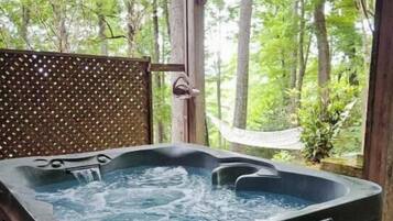 A hot tub in a covered outdoor area with a view of a forest.