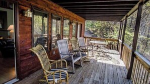 A wooden deck with wicker chairs and a table, overlooking a forested area. - Stay Near Asheville's PGA TOUR – Hot Tub & Access to the Mtn to Sea Trail (Asheville)