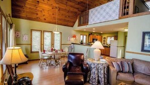 A spacious living room with a high ceiling, a dining area, and a kitchen visible through an open door. - Stay Near Asheville's PGA TOUR – Hot Tub & Access to the Mtn to Sea Trail (Asheville)