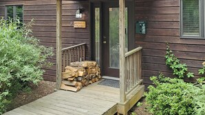Una cabaña rústica con terraza de madera, un porche cubierto y un letrero que dice "Michael's Hide-Away".