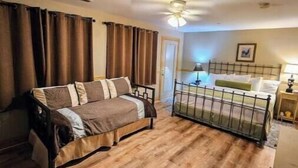A bedroom with a bed, a sofa, a small table, and a ceiling fan. - Perfect Honeymoon cabin w/hot tub (Asheville)