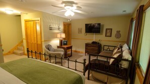 Une chambre à coucher comprenant un lit, une chaise, une commode, un téléviseur et un ventilateur de plafond.