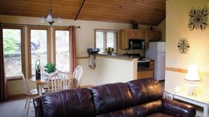 A cozy living area with a leather sofa, wooden ceiling, and a dining table with chairs. - Romantic getaway w/hot tub (Asheville)