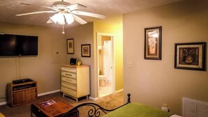A bedroom with a bed, a ceiling fan, a dresser, a television, and framed pictures on the wall. - Romantic getaway w/hot tub (Asheville)