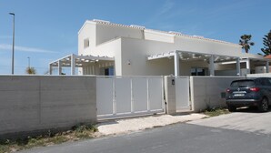 A modern building with a white facade, a gated entrance, and a parked car. - Villa Green - Zannafondo Villas with private garden and 100 mt from the beach (Kaukana)