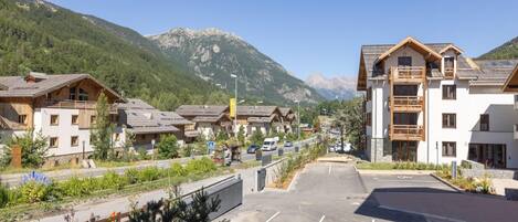 A mountain resort with chalet-style buildings, a parking lot, and a view of the mountains.