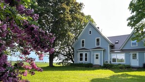 A two-story house with a large lawn and a tree with pink flowers.