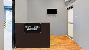 Een receptiebalie met de aanduiding 'TOWNHOUSE', een bedrijfsbord, een aan de muur bevestigde flatscreen-tv en een houten vloer.