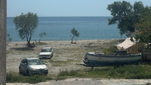 A coastal view with parked cars, a boat, and a clear sky. - KYNTHIA seaview apartments (Samos)