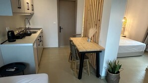 A modern, compact living space with a kitchenette, a dining area, and a bed. - KYNTHIA seaview apartments (Samos)