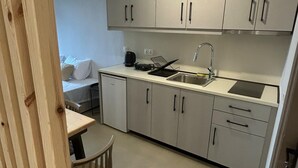 A modern kitchen with light grey cabinets, a stainless steel sink, and a black kettle. - KYNTHIA seaview apartments (Samos)