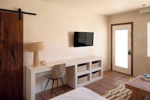 Un dormitorio con una cama, un escritorio con una silla, un televisor y una puerta.