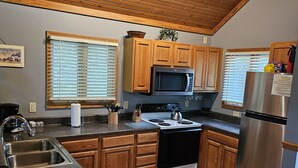 A kitchen with wooden cabinets, a stainless steel refrigerator, a microwave, and a stove.