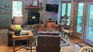 A cozy living room with a stone fireplace, leather sofa, and wooden furniture.