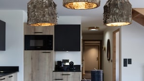 A wooden dining table with a vase and candles, set in a modern kitchen with wooden cabinets and a black countertop. - Apartment in Chantemerle Near Ski Slopes (Saint-Chaffrey)