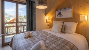 A bedroom with a large bed, a view through a sliding door to the outdoors, and a painting on the wall. - Apartment in Chantemerle Near Ski Slopes (Saint-Chaffrey)