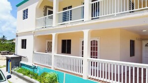 A two-story building with balconies, a pool, and a car parked in front. - 2-Bedroom/Bath Comfortable AI Residence- 
A/C, WiFi and 7 mins away from beach. (Statia Valley)