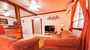 A living room with a sofa, armchairs, a TV, and a lamp. - 2-Bedroom/Bath Comfortable AI Residence- 
A/C, WiFi and 7 mins away from beach. (Statia Valley)